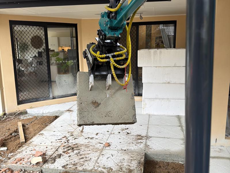The 1.8T lifting a cut slab section clear of a house, the sawn edge of the remaining concrete beside it